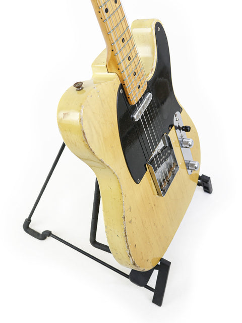 1954 Fender Telecaster 'Blackguard' guitar elegantly positioned on a stand, set against a bright white background.