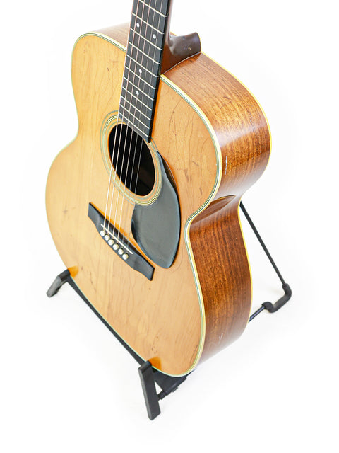 1974 Martin 000-28 guitar on a stand, featuring a minimalist white background for emphasis.