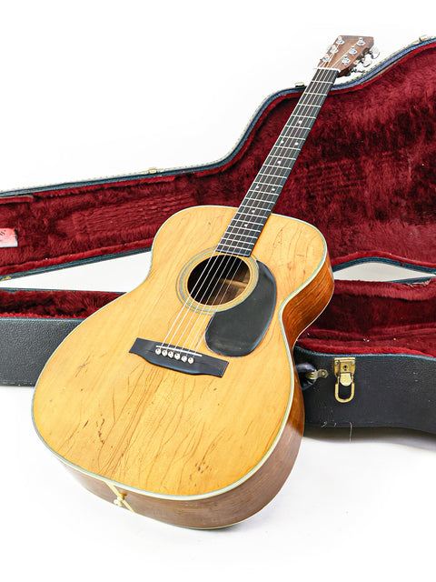 A 1974 Martin 000-28 guitar and case placed on a white surface, exemplifying timeless design and vintage charm.