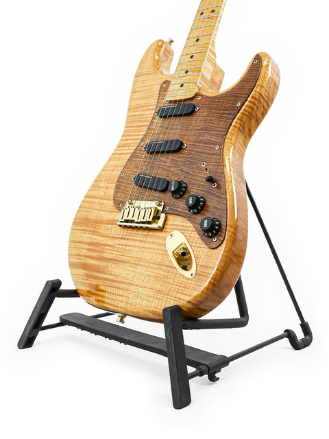 A 1992 Fender Custom Shop 'Clapton' Stratocaster displayed on a black stand, highlighting its iconic shape and finish.