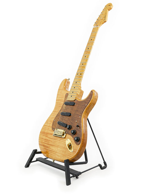 A 1992 Fender Custom Shop 'Clapton' Stratocaster guitar displayed on a stand, set against a minimalist white backdrop.