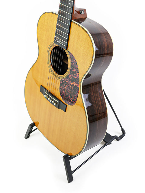 A 2006 Martin 000-28EC Eric Clapton Signature guitar elegantly positioned on a stand with a stark white background.