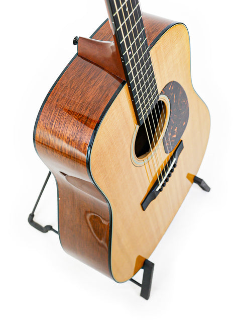 A 2012 Martin D-18 guitar resting on a stand, set against a bright white background, highlighting its craftsmanship.