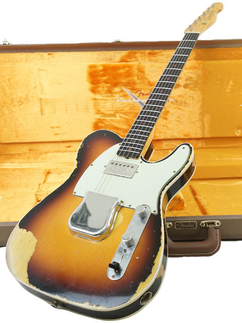 A Fender Custom Shop 60s Telecaster guitar in a case, with another case resting on top, showcasing its aged relic finish.