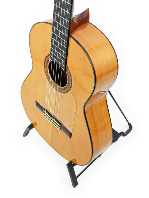 A José Ramírez 2A guitar on a stand against a clean white background, showcasing its elegant design and craftsmanship.