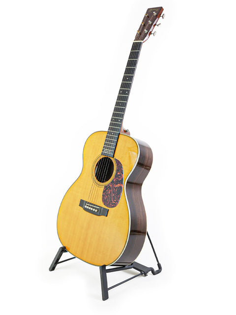 A Martin 000-28EC Eric Clapton Signature guitar displayed on a stand against a clean white background.