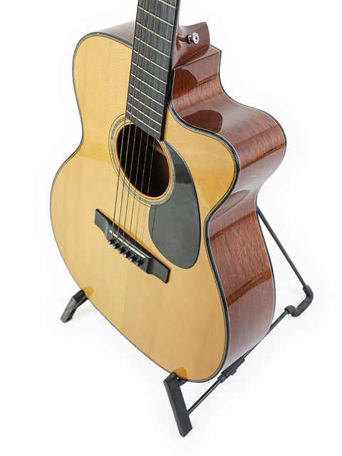 A Martin 000-C David Gray Custom guitar on a stand, set against a clean white background, showcasing its elegant design