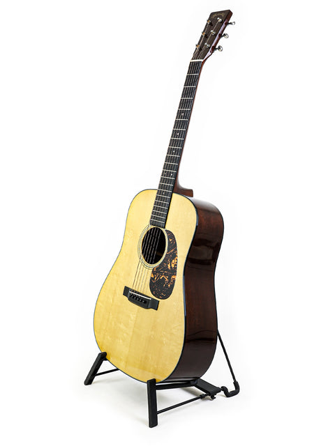 A Martin D-18 Authentic 1937 guitar elegantly displayed on a stand, set against a bright white backdrop, emphasizing its craftsmanship.