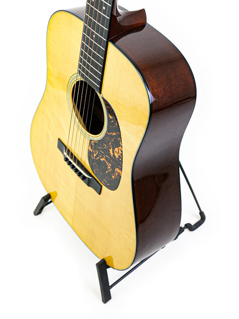 A Martin D-18 Authentic 1937 guitar elegantly positioned on a stand, contrasted by a bright white background for visual clarity.