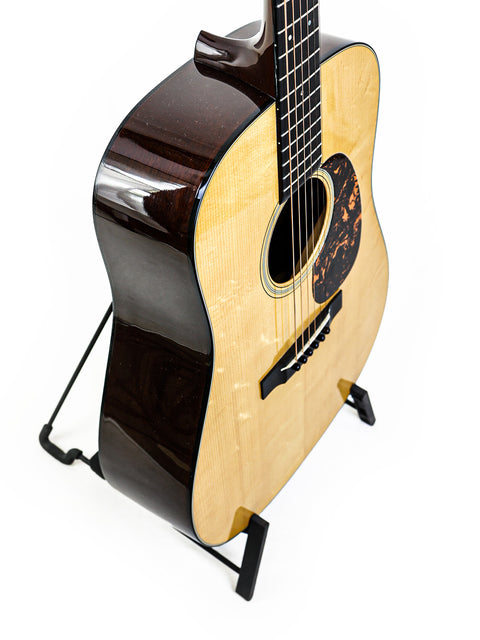 A Martin D-18 Authentic 1937 guitar resting on a stand, set against a bright white background, highlighting its craftsmanship.