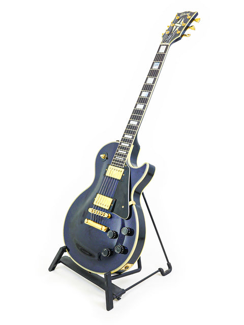 A black electric guitar, a 1991 Gibson Custom Shop Les Paul Custom, elegantly displayed on a stand.