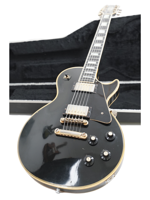A black electric guitar, specifically a 1973 Gibson Les Paul Custom Black Beauty, securely housed in its case.