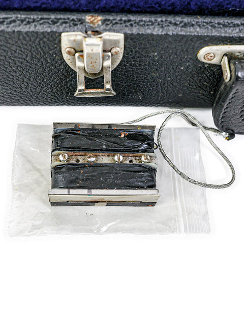 A black suitcase slightly ajar, featuring a classic 1969 Gibson EB-1 guitar resting within.