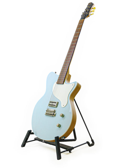 A blue Koll Troubadour guitar elegantly positioned on a stand, set against a bright white background for a modern look