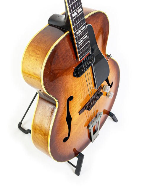 A classic 1946 Gibson ES-300 guitar on a stand, emphasizing its vintage appeal and rich musical heritage.