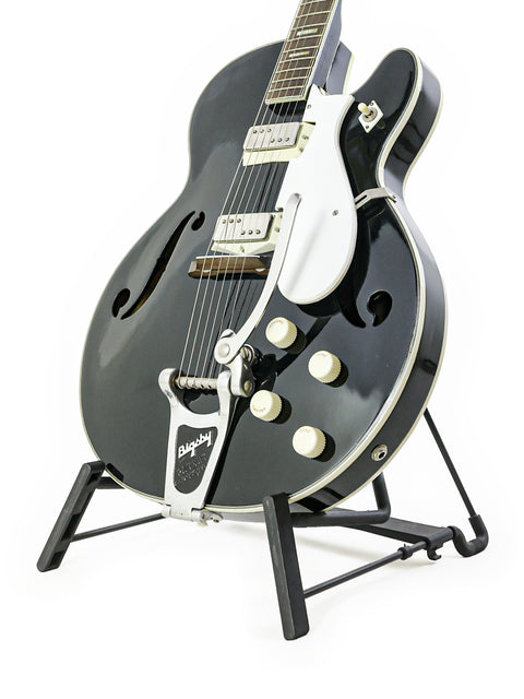 A classic black Silvertone 1446 guitar on a stand, highlighted by a bright white background, perfect for music lovers.