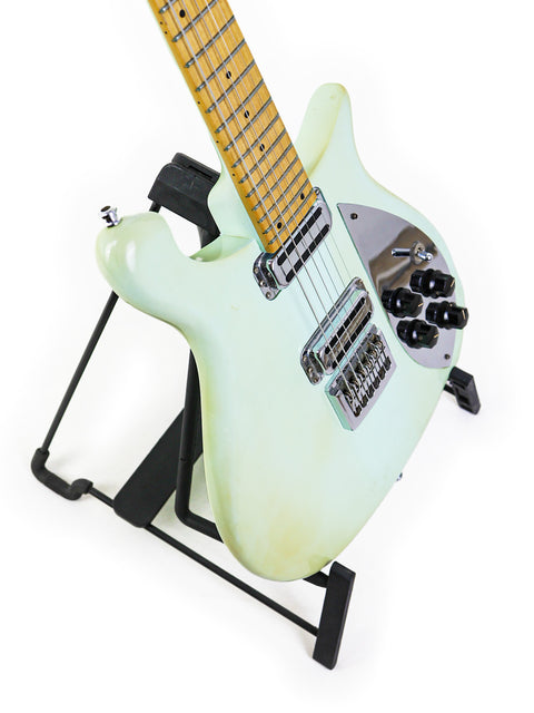 A pristine white electric guitar, the Rickenbacker 650C Colorado 2005, showcased on a stylish stand.