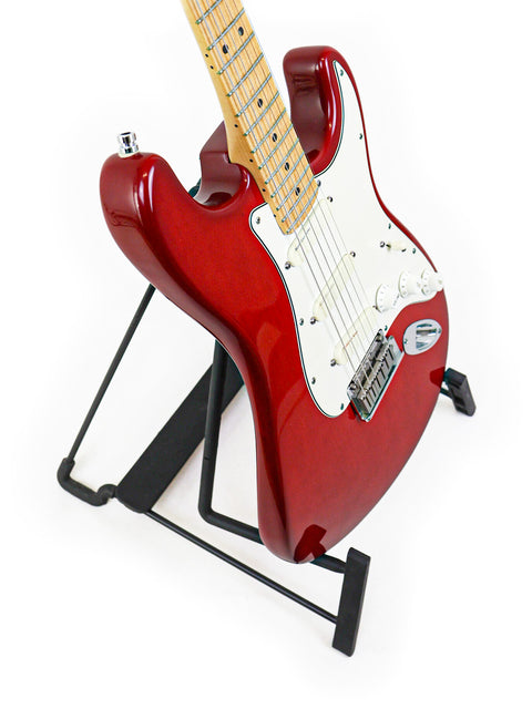 A red 1993 Fender Strat Plus Deluxe guitar elegantly positioned on a stand with a sleek black base.