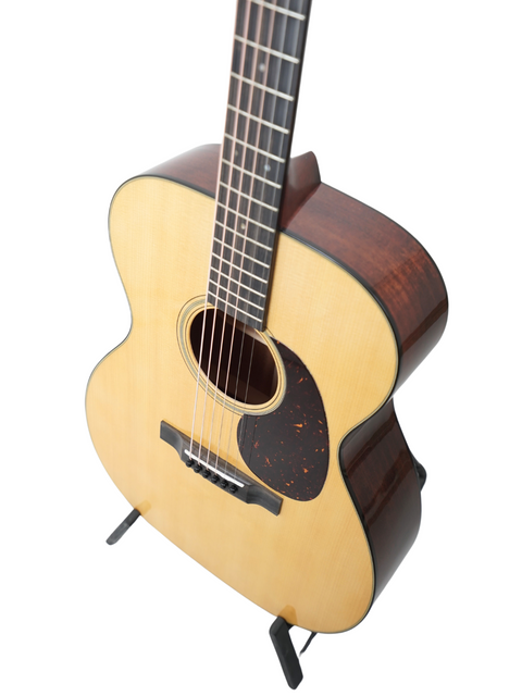 A small acoustic guitar, the Martin 000-18, displayed on a stand, representing fine USA craftsmanship from 2023.