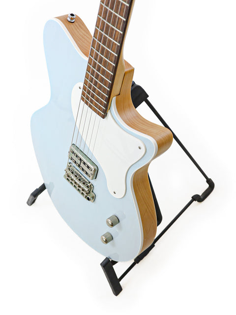 A striking blue electric guitar, the Koll Troubadour from 2013, elegantly positioned on a stand, highlighting its craftsmanship.