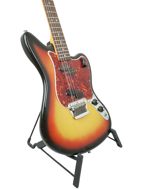 A stunning vintage Fender Electric XII guitar with a sunburst finish, proudly standing on its display stand.