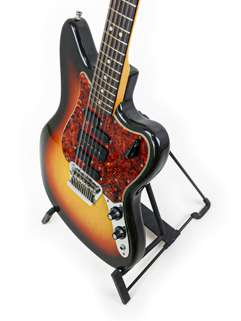 A sunburst-finished 1966 Fender Electric XII guitar on a stand, highlighting its vintage charm and style.