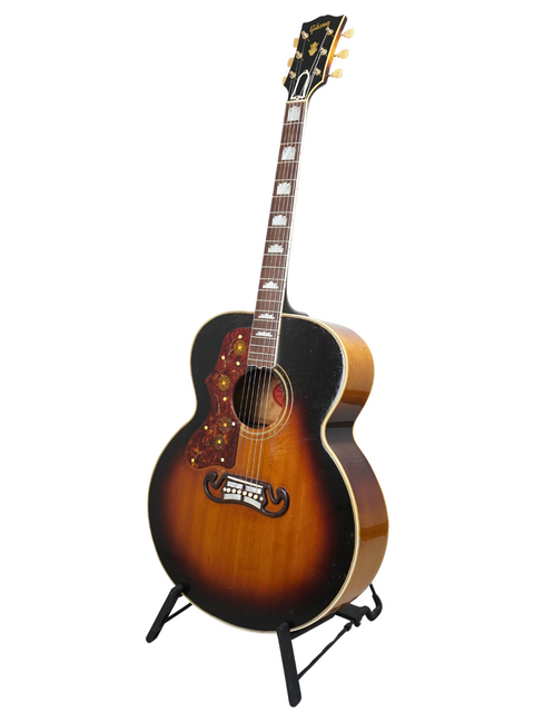 A vintage 1955 Gibson J-200 left-handed guitar showcased on a stand, embodying the essence of classic American craftsmanship.