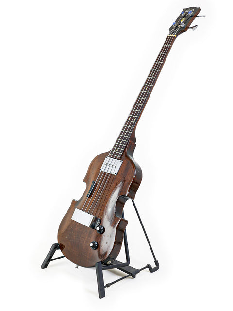 A vintage 1969 Gibson EB-1 guitar resting on a stand, featuring a beautiful wooden finish and classic design elements.