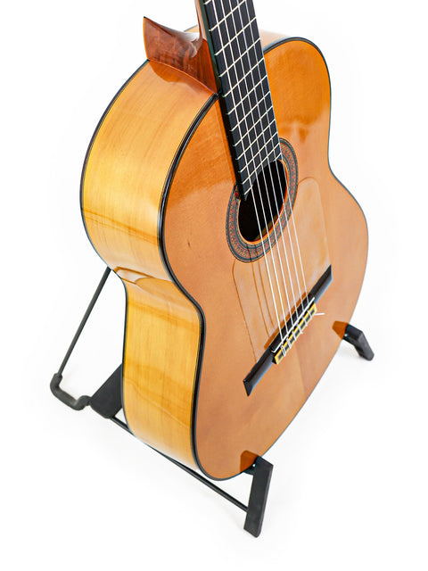 A vintage José Ramírez 2A guitar displayed on a stand, set against a stark white background, highlighting its classic features.