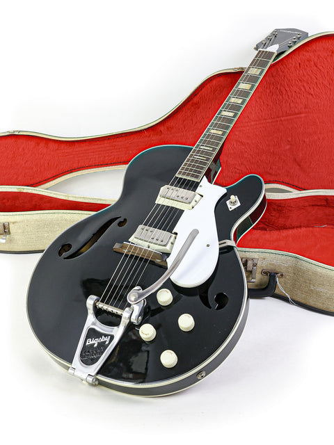 A vintage black Silvertone 1446 guitar from 1961-65, elegantly placed in a bold red case, ready for a jam session.