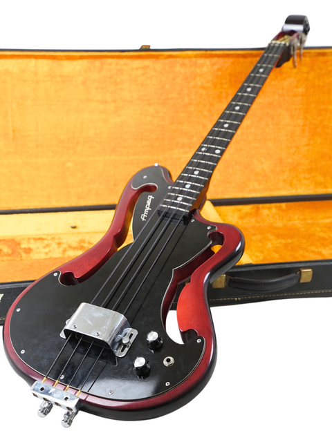 A vintage electric guitar in black and red, securely placed in a case, representing the 1966 Ampeg AEB-1 bass.