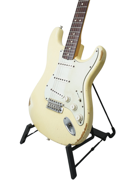 A white '64 Stratocaster Relic guitar on a black stand, highlighting its unique design from the Fender Custom Shop, USA 2009.