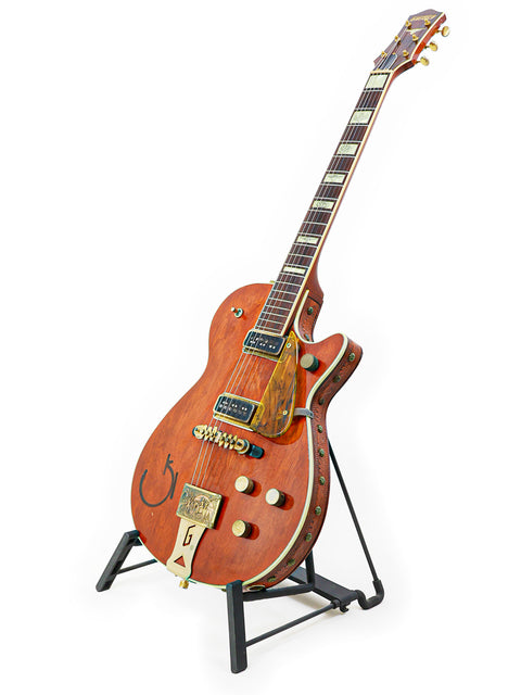 A wooden-bodied Vintage Gretsch 6130 Roundup guitar from 1955, elegantly positioned on a stand.