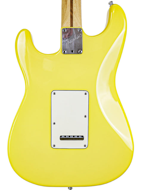A yellow electric guitar body with a visible wood neck and branded neck plate.