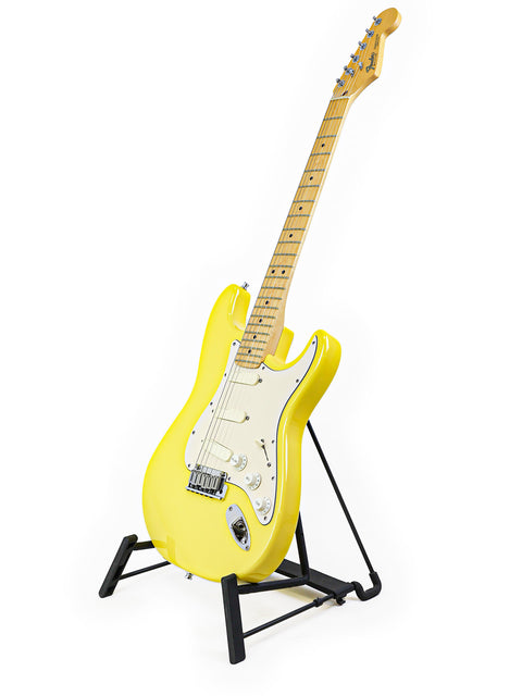 A yellow electric guitar on a black stand against a white background.