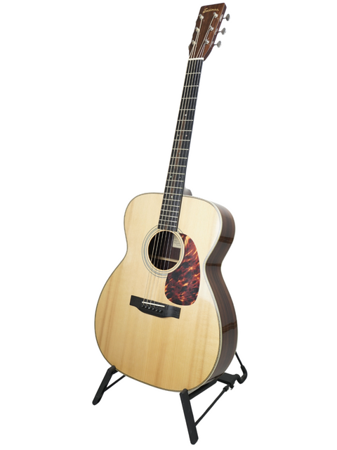 Acoustic guitar on stand against a white background.