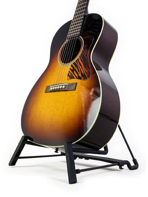 Acoustic guitar on stand with sunburst finish against a white background.