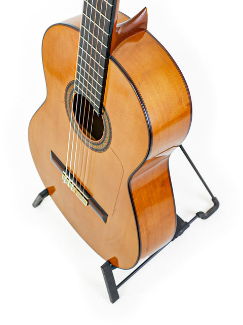 An elegant guitar set against a white backdrop, emphasizing its design and the legacy of M.G. Contreras, Calle Mayor 80, Spain, 1973.