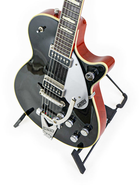 Beautifully crafted black and red Gretsch Duo Jet 6128TSP guitar on a stand, a must-have for serious guitar players.