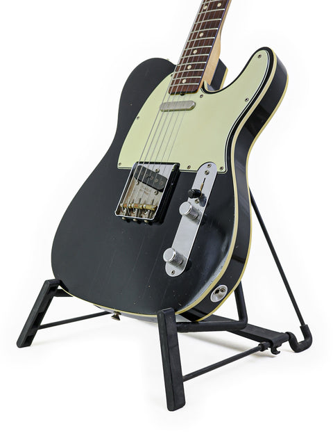 Black Fender '59 Custom Telecaster guitar displayed on a stand with a white backdrop.