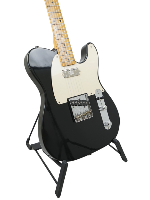 Black electric guitar with a maple neck on a stand, isolated on a white background.