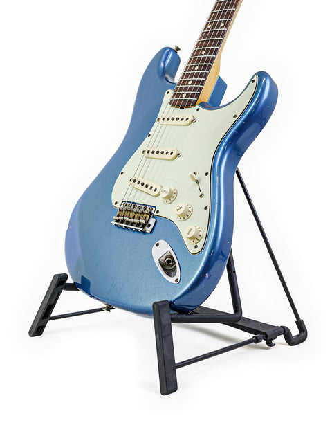 Blue '62 Stratocaster Relic guitar on a stand, featuring a white background, showcasing its vintage design.