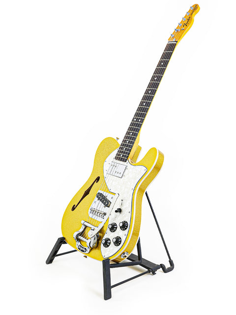Bright yellow guitar on a stand with a white backdrop, featuring the Txxx Custom Thinline '72 Partscaster with B5 Bigsby.