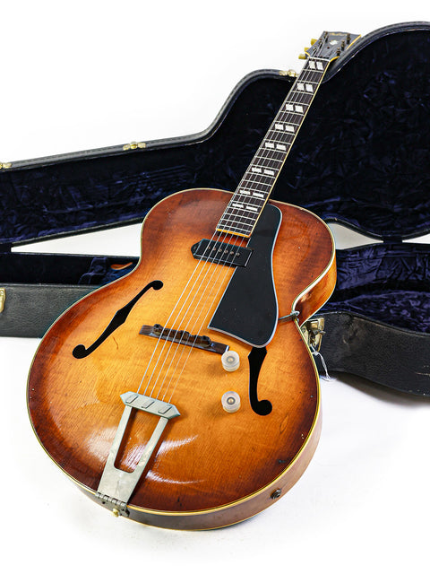 Classic 1946 Gibson ES-300 guitar in a case, beautifully positioned on a white surface, exuding vintage charm.