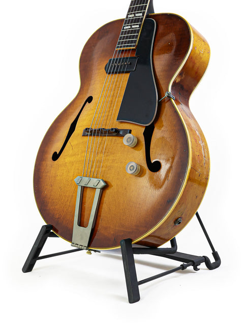Classic 1946 Vintage Gibson ES-300 guitar resting on a stand, featuring a striking white background that enhances its charm.