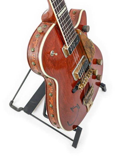 Classic 1955 Gretsch 6130 Roundup guitar featuring a wooden body, resting on a metal stand, highlighting its vintage appeal.