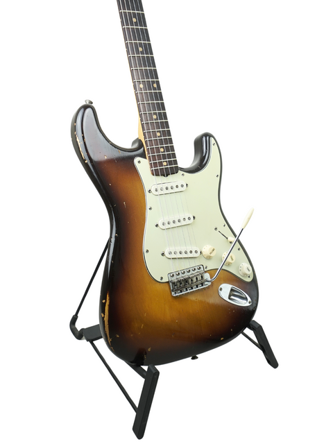 Classic 1959 Fender Stratocaster guitar on a stand, featuring a slab board and showcasing its timeless vintage appeal.