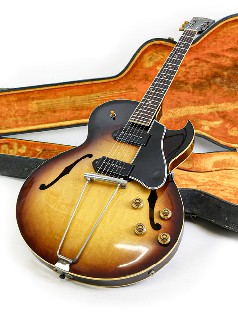 Classic 1959 Gibson ES-225TD guitar with its case, beautifully positioned on a white surface for a timeless look.