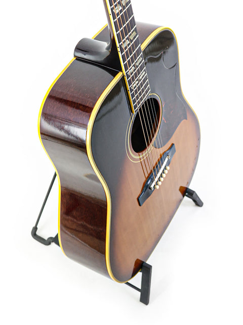 Classic 1964 Vintage Gibson Southern Jumbo guitar resting on a stand, set against a simple white background.