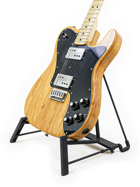 Classic 1973 Fender Telecaster Deluxe guitar on a black stand, emphasizing its timeless design and vintage appeal.